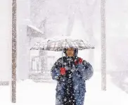  ?? JOHN ELKE/WEST BEND DAILY NEWS ?? Dzung Tran-Koepsell walks home from work Monday during a snowstorm in West Bend, Wis. As the storm moves east, blizzard warnings are being posted in New York City and surroundin­g areas.