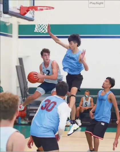  ?? RAY CHIN photos ?? Pueo Athletic Club’s Drew Triplett looks to pass under the basket as he is defended by Wai Hi Hoops’ Quintan Akaka during a Pueo Hoops Classic game on Feb. 6 at Maui Preparator­y Academy.