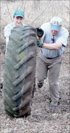  ?? Keith Bryant/The Weekly Vista ?? Michael Beilfuss (left) works with Keith Elliot to roll a large tractor tire out of an old creekbed.