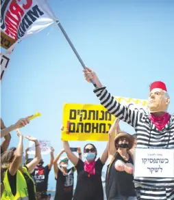  ?? ( Miriam Alster/ Flash90) ?? ISRAELIS DEMONSTRAT­E against the three- week nationwide lockdown and Prime Minister Benjamin Netanyahu, on a Tel Aviv beach on Saturday.