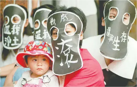  ?? TAO- CHUAN YEH/GETTY IMAGES ?? Members of the Yami people, wearing black masks, protest the storage of nuclear waste on their home of Orchid Island. The words on the masks read “Get out” and “Need surviving places.” The island, part of Taiwan, saw more than 220,000 visits during the pandemic.