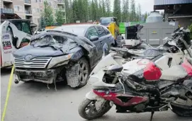  ?? Tijana Martin/calgary Herald. ?? A damaged vehicle and muddy motorcycle­s at the Wedge Woods complex in Discovery Ridge on Wednesday.