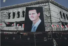  ?? Reuters ?? A large poster of Bashar Al Assad stands in front of a damaged building in the city of Douma, Syria