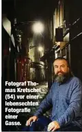  ??  ?? Fotograf Thomas Kretschel (54) vor einer lebensecht­en Fotografie einer Gasse.