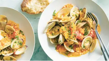  ?? ?? Fresh clams cook with garlic, white wine, shallots and tomatoes to form a deliciousl­y fragrant sauce.