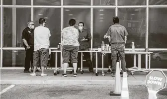  ?? Cengiz Yar / Getty Images ?? Zeke Salazar, center, gives job search informatio­n to people outside the Workforce Solutions Borderplex North Loop Center in El Paso on Thursday.