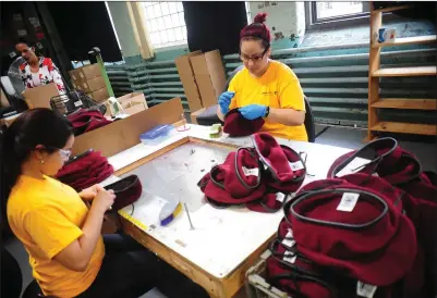  ?? Ernest A. Brown photo ?? Scarleth Sanchez, left, and Abigail Colon are busy working on berets for the Defense Department at H. Brickle and Son in Woonsocket Wednesday afternoon. The two were on display during a tour of the operation by Gov. Gina Raimondo on Wednesday.