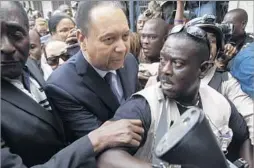  ?? Dieu Nalio Chery Associated Press ?? RETURN FROM EXILE “Baby Doc” Duvalier, center, the son of Francois “Papa Doc” Duvalier, is surrounded by police as he arrives at court in Port- au- Prince on Jan. 18, 2011.