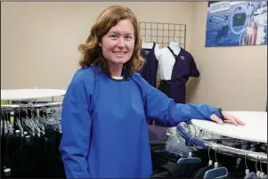  ?? The Associated Press ?? SUPPLY CHAINS: Ann Quigley stands Tuesday in a waterproof gown intended for milking cows made by Udder Tech Inc. a Rosemount, Minnesota-based dairy supply company. Minnesota bought 2,300 waterproof gowns intended for milking cows from Udder Tech Inc. The special gowns cost about $46 each when freight was included.