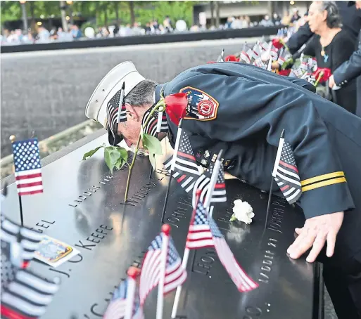  ?? DAVID HANDSCHUH THE ASSOCIATED PRESS ?? Retired paramedic chief Charlie Wells kisses the name of a relative who was killed on 9/11 at the National September 11 Memorial in New York.