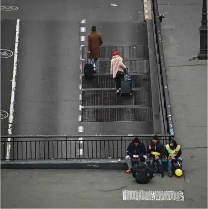  ?? (OLIVIER MORIN/AFP) ?? Des voyageurs croisent des «gilets jaunes» à la place de la Bourse, à Paris.