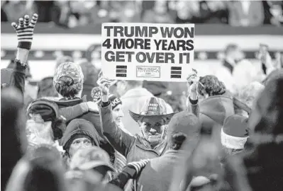  ?? DAMON WINTER/THE NEW YORK TIMES ?? A supporter of former President Donald Trump holds up a sign Dec. 5 in Valdosta, Georgia.