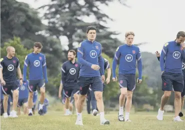  ??  ?? 0 Harry Maguire, centre, looks on during a recovery walk at St George’s Park earlier this week