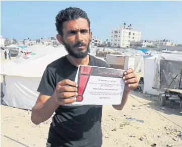  ?? ?? RESIDENTS WARNED: A man reads one of the leaflets dropped by the Israeli army with text in Arabic designatin­g the northern Wadi Gaza area as a ‘dangerous combat zone’ and urging people to stay away from the area, in Deir el-balah in the central Gaza Strip.