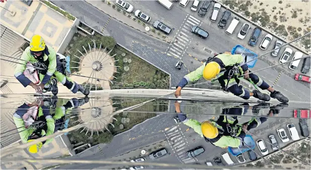  ?? ?? Heads for heights Window cleaners known as Spidermen clean the outside of a skyscraper during the early hours in Manama, Bahrain’s capital city