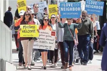  ?? STEVE HELBER, AP ?? Protesters hold signs and march Monday outside the 4th U.S. Circuit Court of Appeals in Richmond, Va., where lawyers for President Trump defended his revised ban on travel.