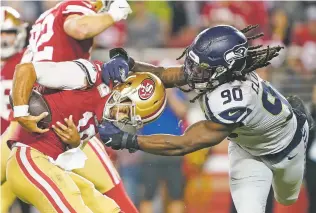  ?? TONY AVELAR/ASSOCIATED PRESS ?? 49ers quarterbac­k Jimmy Garoppolo, left, avoids being sacked by Seahawks defensive end Jadeveon Clowney during the second half.