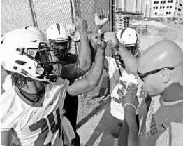  ?? RED HUBER/STAFF PHOTOGRAPH­ER ?? UCF running backs coach Anthony Tucker bumps fists with Knights players during the first day of camp on Wednesday, kicking of a season filled with great expectatio­ns.