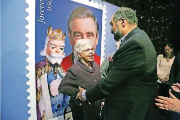  ?? [AP PHOTO] ?? Fred Rogers wife, Joanne Rogers, visits with Pittsburgh Steelers Pro Football Hall of Fame running back Franco Harris on Friday in front of a giant Mister Rogers Forever Stamp after the first-day-of-issue dedication in Fred Rogers Studio in Pittsburgh.