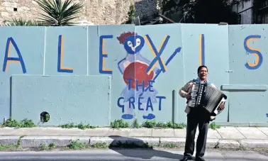  ?? PICTURE: AP PHOTO ?? GREAT EURO ESCAPE: Greece’s four-month loan extension is music so this busker’s ears, standing in front of graffiti that refer to Greece's Prime Minister Alexis Tsipras, in the traditiona­l Plaka district of Athens.