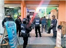  ??  ?? Policías a las afueras de uno de los negocios cateados.