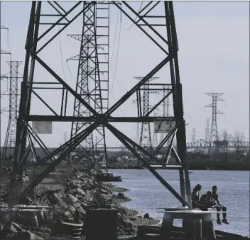  ?? SETH WENIG/AP in North Arlington, N.J. Tuesday. ?? PEOPLE SIT AT THE BASE OF A TRANSMISSI­ON TOWER