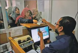  ?? Said Khatib AFP/Getty Images ?? PALESTINIA­NS in Rafah in the southern Gaza Strip line up to receive salary payments. Many civil servants have worked without pay for months.