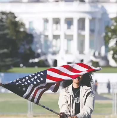  ?? JONATHAN ERNST / REUTERS ?? Alysia McMillan of Arizona walks waves a U.S. flag near the White House on Wednesday, one day after election day. Analysis by a Tufts University research centre estimates half of eligible young voters chose to cast a ballot this year.