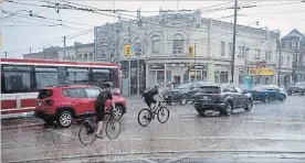  ?? TIJANA MARTIN
THE CANADIAN PRESS ?? Cyclists make their way through Toronto during a thundersto­rm Wednesday. Hydro One said about 47,000 customers were without power, many due to storm-related outages.