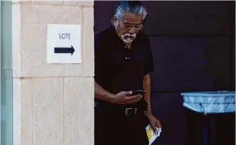  ?? Jessica Phelps/staff photograph­er ?? Joe Lopez checks his phone as he leaves the Westside Public Library in New Braunfels after voting in Tuesday’s primary. Drama was in short supply in local races.