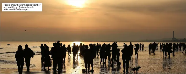 ?? Mike Hewitt/getty Images ?? People enjoy the warm spring weather and low tide on Brighton beach.