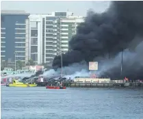  ?? Satish Kumar / The National ?? Smoke billows out across the pier as firefighte­rs tackle a boat fire in Dubai Creek.