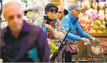  ?? HOWARD LIPIN U-T PHOTOS ?? Charlene Pless of North Park is flanked by other shoppers at Barons Market in North Park during the seniors-only time, one hour before the store opened to the general public on Friday.