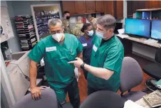  ?? DAVID J. PHILLIP/ASSOCIATED PRESS ?? Registered nurses Army Lt. Col. Oswaldo Martinez, left, and Maj. Andrew Wieher, right, with the Urban Augmentati­on Medical Task Force, work to set up a nurses station.