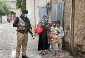  ?? — AP ?? a police officer stands guard while a healthcare worker administer­s a polio vaccine to a child in Peshawar, Pakistan – one of two countries in the world where the infectious disease is still endemic.