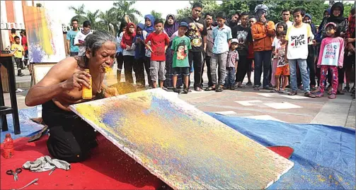  ?? GHOFUUR EKA/JAWA POS ?? TETAP INDAH: Soegeng Prajitno melukis dengan teknik menyemburk­an cat dari mulut di Alun-Alun Sidoarjo kemarin.