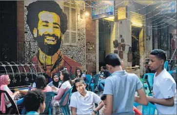  ?? Photograph­s by Jonathan Rashad For The Times ?? FANS GATHER in front of a mural of star forward Mohamed Salah in Cairo for the Uruguay-Egypt match.