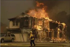  ?? JEFF CHIU — THE ASSOCIATED PRESS FILE ?? In this file photo, a firefighte­r walks near a flaming house in Santa Rosa The long and brutal 2017 wildfire season is stressing the state and federal agencies that have to pay for the army of ground crews and machinery required to fight them.