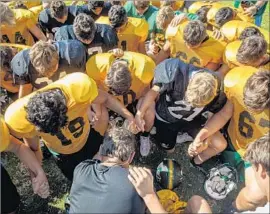  ??  ?? A TEAM PRAYER is held after practice. The coach, Jay Seibert, decided a few days after the hurricane that his team would play its season opener.