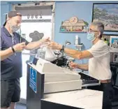  ?? AMY BETH BENNETT/SOUTH FLORIDA SUN SENTINEL ?? Former owner Evangelo Karaliolio­s makes change for Rolando Descoteaux as he picks up a takeout order at Andrews Diner in Wilton Manors in April.