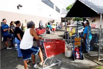  ??  ?? Paul Akamine fills propane tanks as customers line up as Hurricane Lane approaches Honolulu. — AFP photo