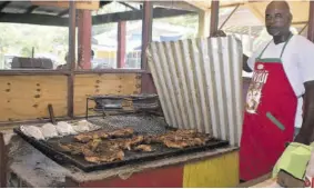  ?? (Photos: Everard Owen) ?? Jerk vendor Garth Neufville displays jerk chicken and fish.