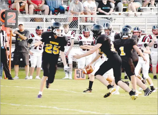  ?? PHOTOS BY MARK HUMPHREY ENTERPRISE-LEADER ?? Prairie Grove quarterbac­k Caleb Carte hands off to Luke Bannon. After Prairie Grove fumbled the opening kickoff, the junior Tigers struggled through the first half before rallying to notch a 24-6 nonconfere­nce win over Pea Ridge in the junior high football season opener Thursday.