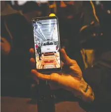  ?? AARON VINCENT ELKAIM/ THE CANADIAN PRESS ?? A worker shows a photo of the last truck to be assembled at the General Motors production line in Oshawa, Ont., while at a sports bar with colleagues on Wednesday.