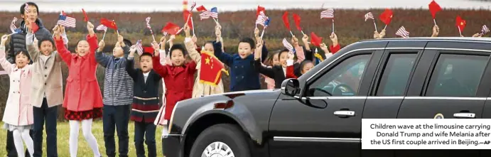  ?? AP ?? Children wave at the limousine carrying Donald Trump and wife Melania after the US first couple arrived in Beijing.—