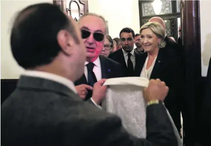  ?? Hussein Malla / AP Photo ?? An aide of Lebanon’s grand mufti Sheikh Abdellatif Deryan offers a headscarf to Marine Le Pen in Beirut yesterday.