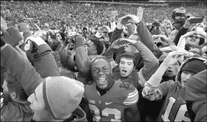  ??  ?? Ohio State players and fans rejoice after the Buckeyes beat rival Michigan for the fifth year in a row.