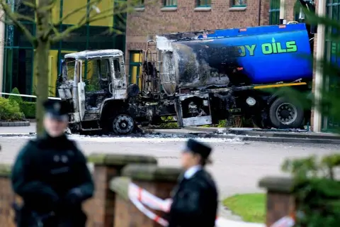  ??  ?? TERRORISED: Left, a burnt-out oil truck that was rammed into the headquarte­rs of the Aventas Group (formerly known as the Quinn Group) in Derrylin, Co Fermanagh, in 2013; above, a Garda cordon after the attack on Kevin Lunney, right, last month
