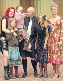  ??  ?? Proud Midge collecting his OBE in 2005 with his wife Sheridan and daughters Molly, Ruby, Flossie and Kitty