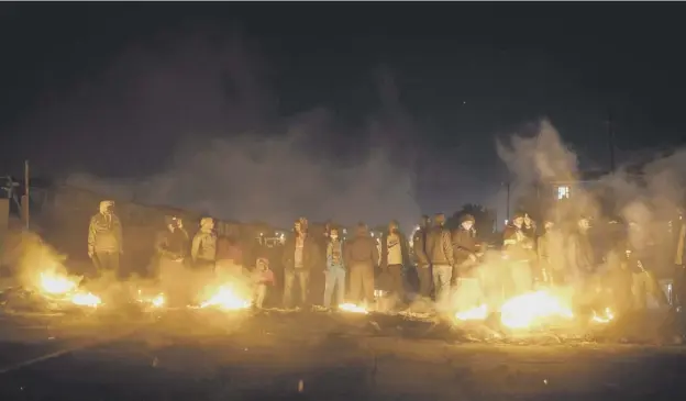  ??  ?? Armed community members gather around a fire at a road block set up in Phoenix Township, North Durban to prevent looters from reaching the community